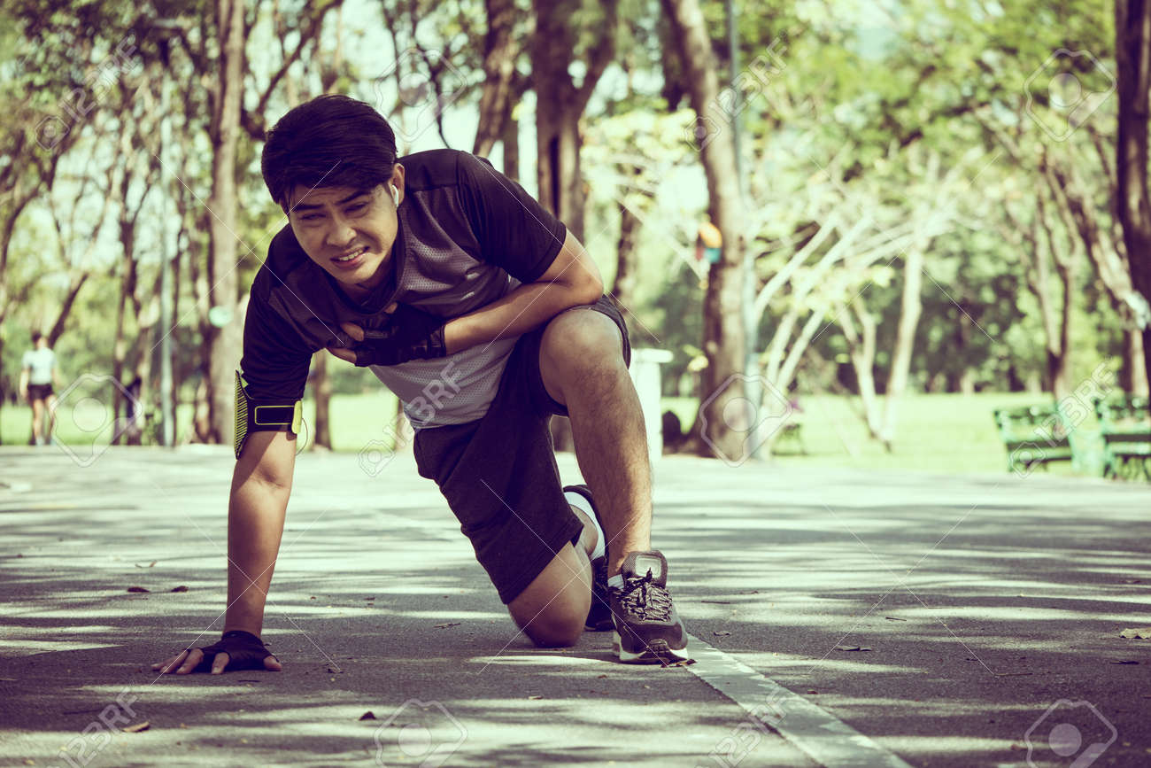 An Asian man has a heart pain while exercising in a park. - 94426271 An Asian man has a heart pain while exercising in a park. - 94426271