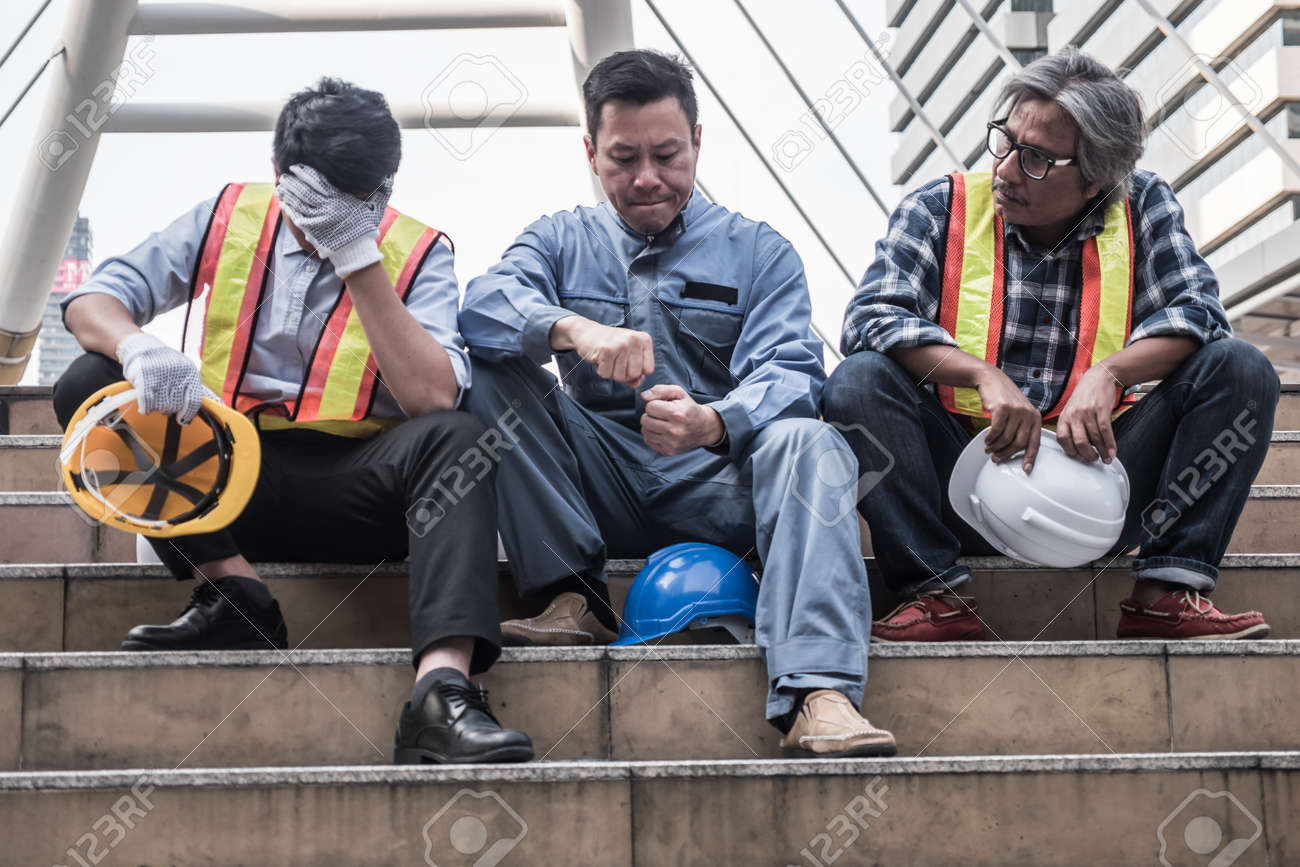Unhappy engineer sitting on building stairs at construction site, They feel tired and stressed from work. - 94922991 Unhappy engineer sitting on building stairs at construction site, They feel tired and stressed from work. - 94922991