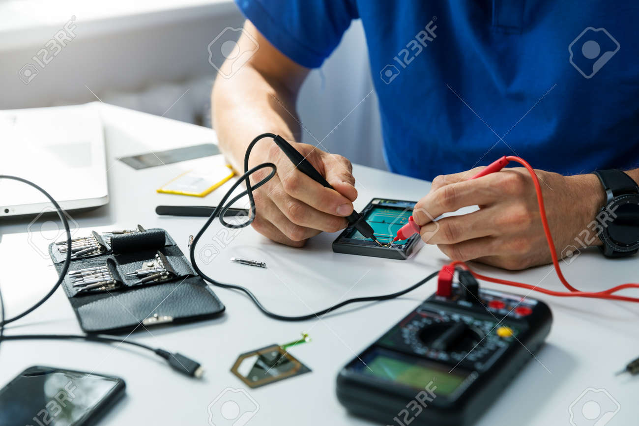 smartphone repair technician check the the phone with multimeter