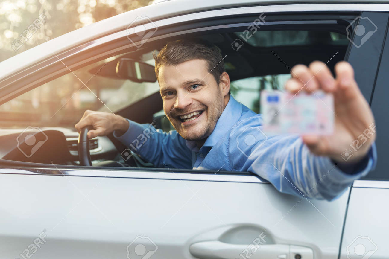 man sitting in the car and showing his driver license out of car window - 136326830 man sitting in the car and showing his driver license out of car window - 136326830