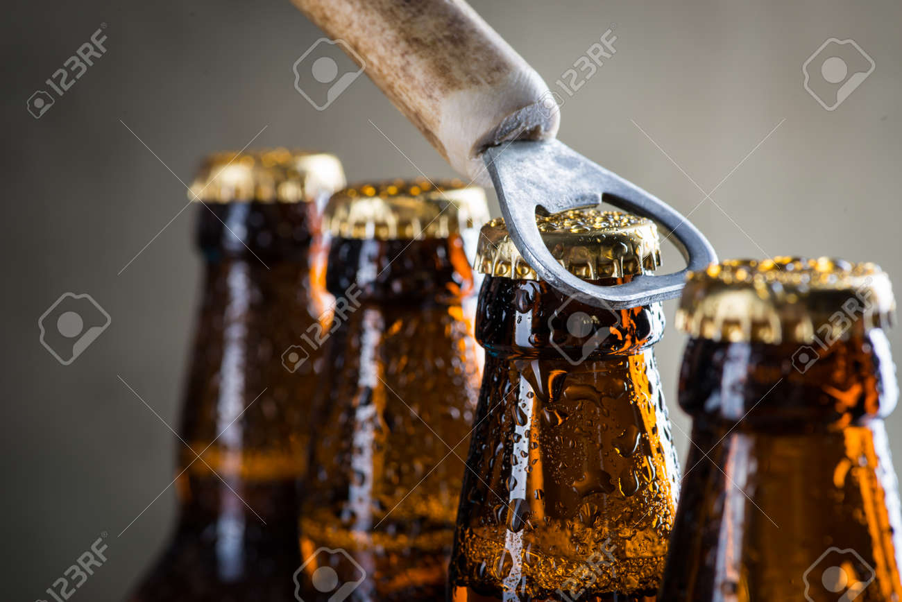 Brown ice cold beer bottles with water drops and old opener - 54104302 Brown ice cold beer bottles with water drops and old opener - 54104302