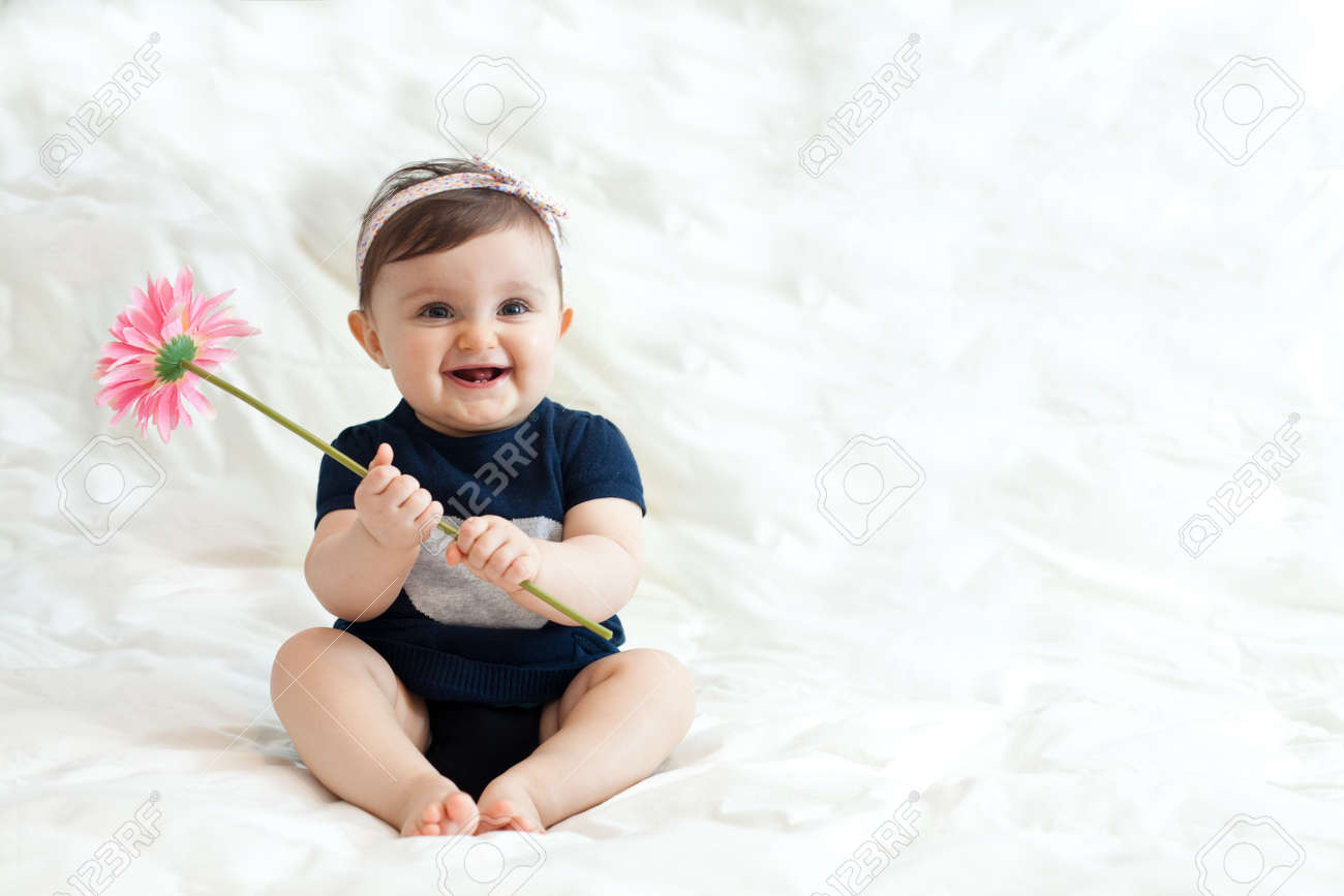 Portrait of cute baby girl 6 11 months playing with flower stock photo