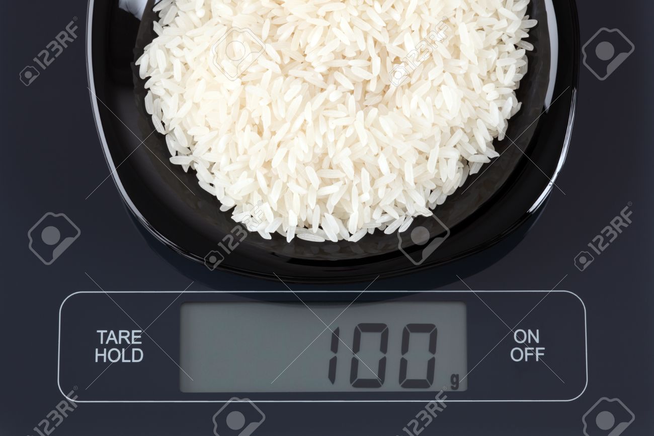 Stock P O White Rice In A Black Plate On Digital Scale Dis100 Gram Stock P O White Rice In A Black Plate On Digital Scale Dis100 Gram