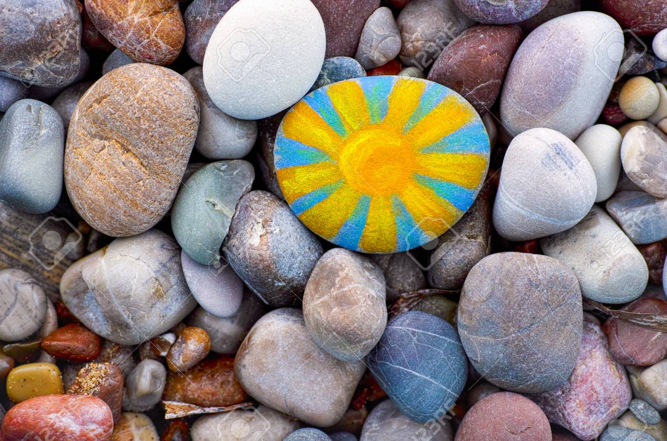 Bright sun painted on pebble. Pebbles background. - 90180565 Bright sun painted on pebble. Pebbles background. - 90180565