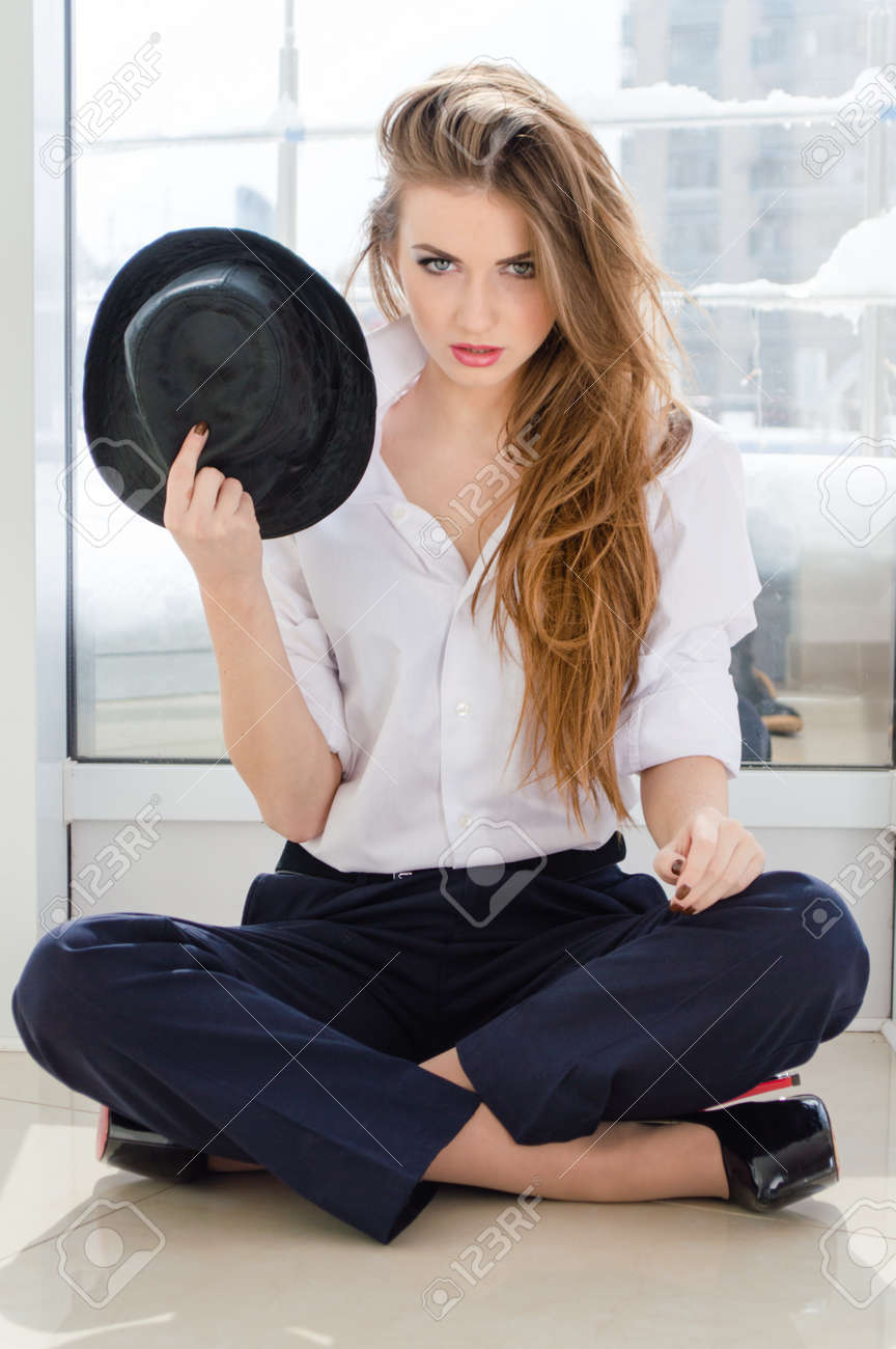 Young business woman looking bossy wearing man's shirt holding stylish hat in office - 19811872 Young business woman looking bossy wearing man's shirt holding stylish hat in office - 19811872