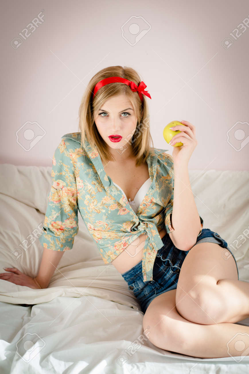 アップルを押しベッドで魅惑的な座っているかなりロカビリー ピンナップ ガール の写真素材 画像素材 Image