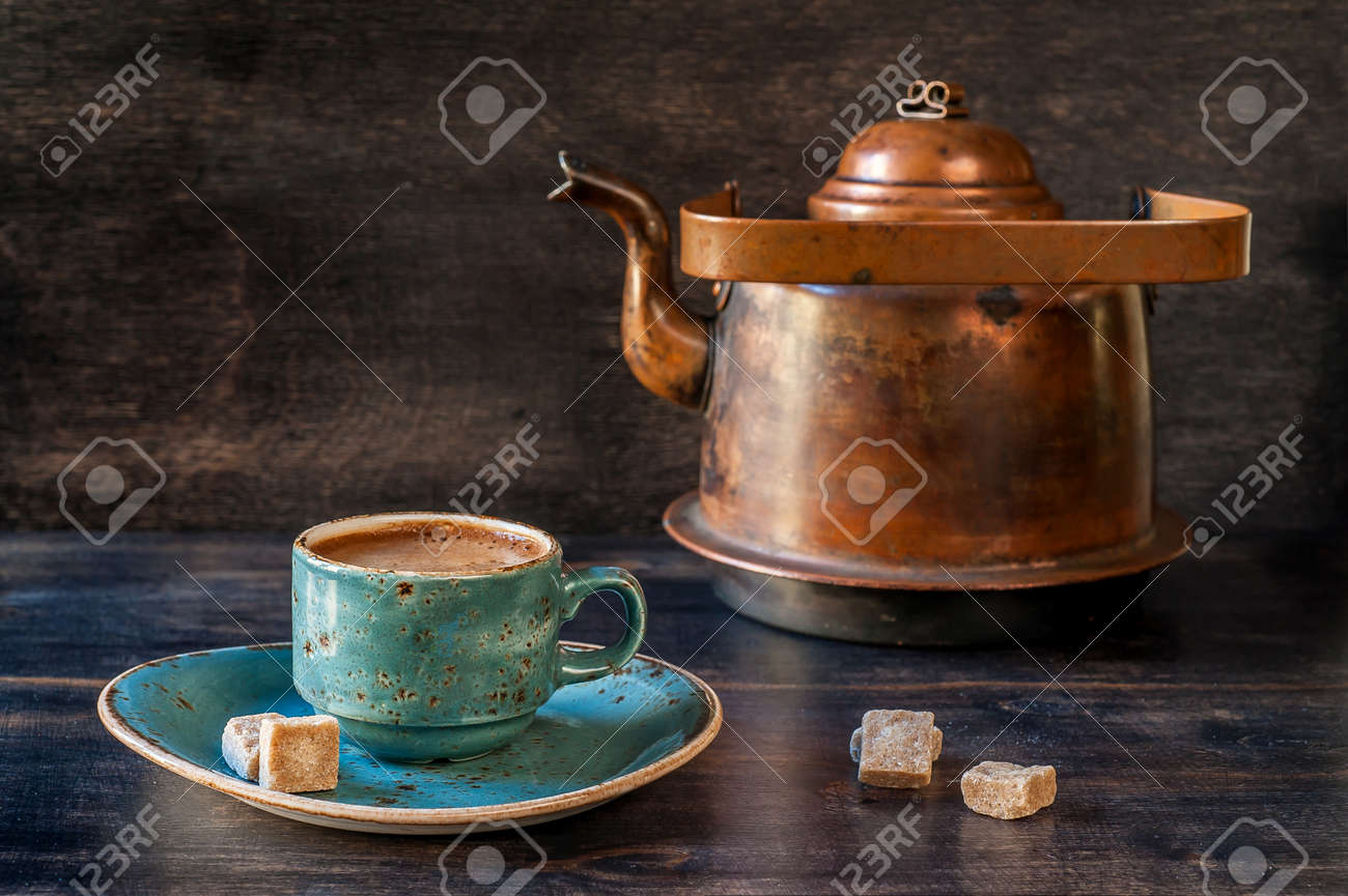 Espresso coffee in a blue cup and old kettle on a wooden board - 25784770 Espresso coffee in a blue cup and old kettle on a wooden board - 25784770