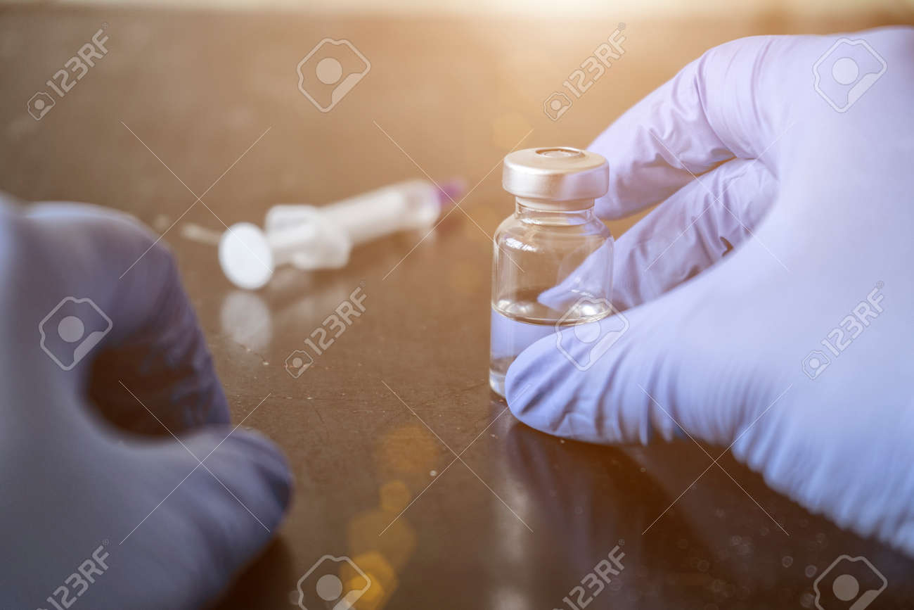 Doctor fills a syringe from an ampoule - 151622216 Doctor fills a syringe from an ampoule - 151622216