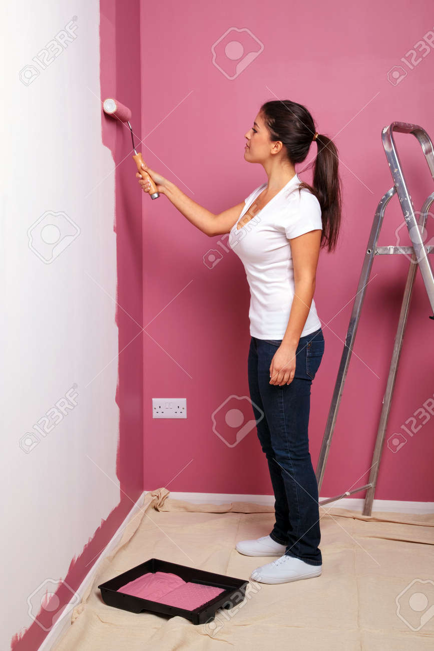 Woman Home Decorating an attractive young woman decorating the wall of her new home Woman Home Decorating an attractive young woman decorating the wall of her new home