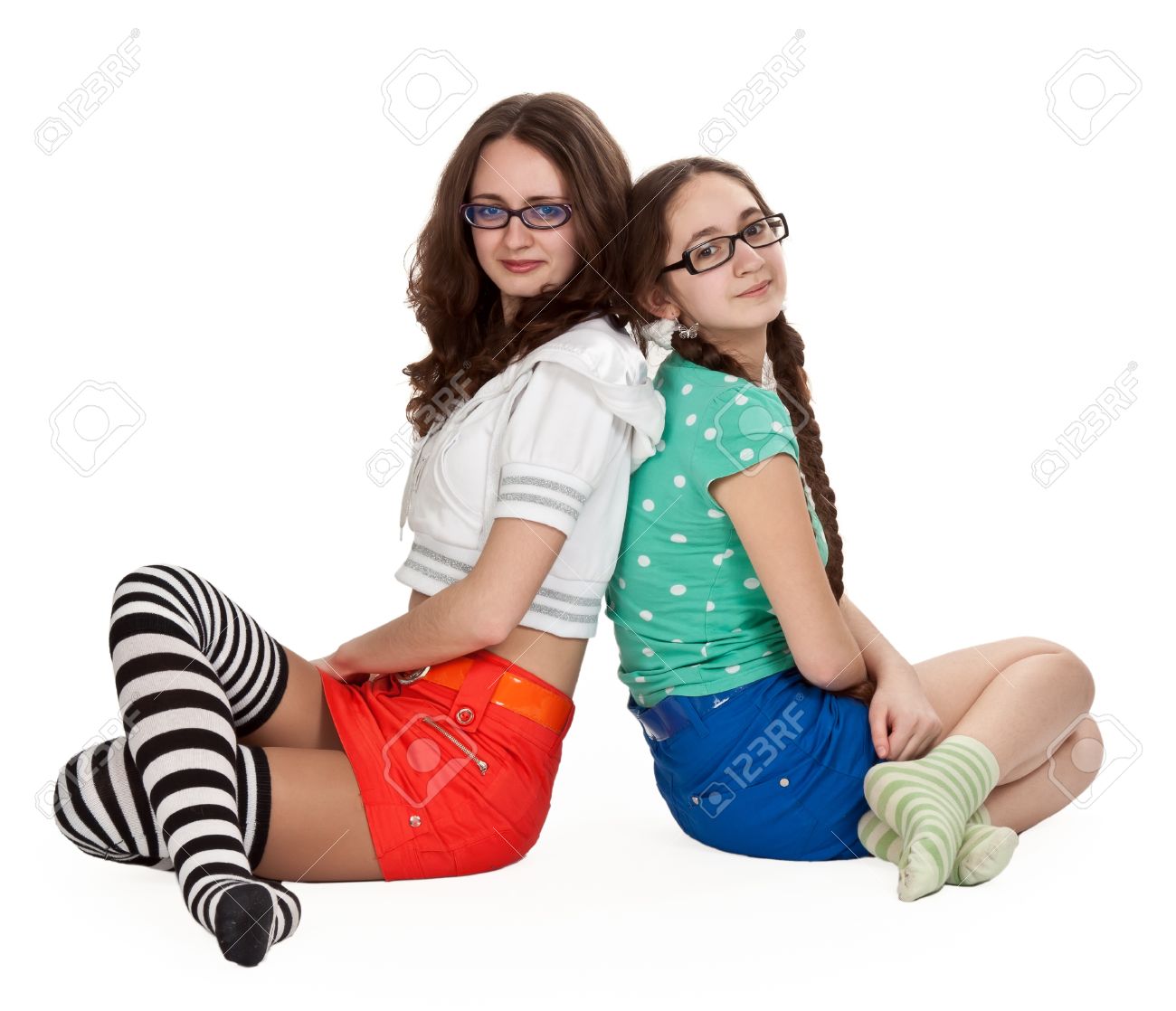 Stock Photo Two Girls Are Sitting On A White Floor In Colored Skirts And Striped Socks Stock Photo Two Girls Are Sitting On A White Floor In Colored Skirts And Striped Socks