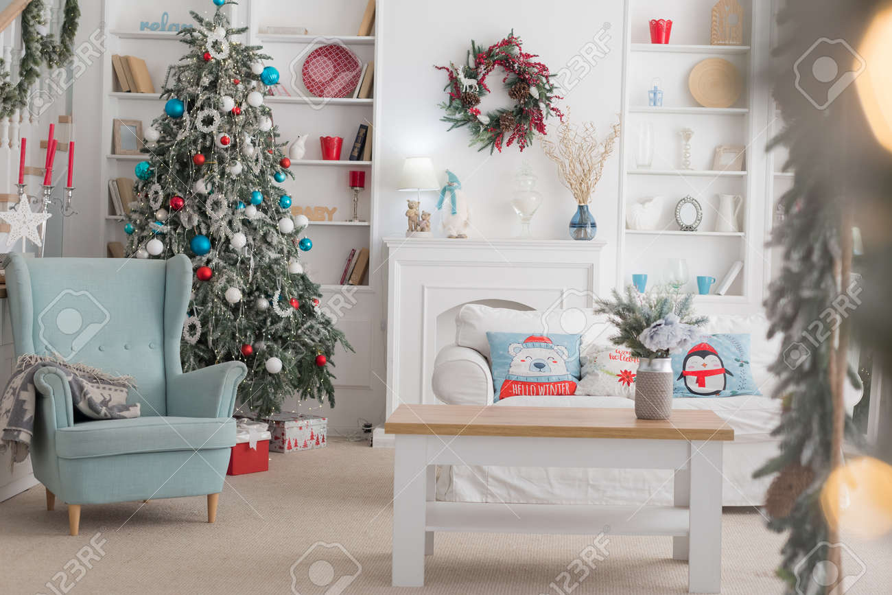 The interior of the Christmas room, a white sofa with pillows at the coffee table and a blue chair - 136133258 The interior of the Christmas room, a white sofa with pillows at the coffee table and a blue chair - 136133258