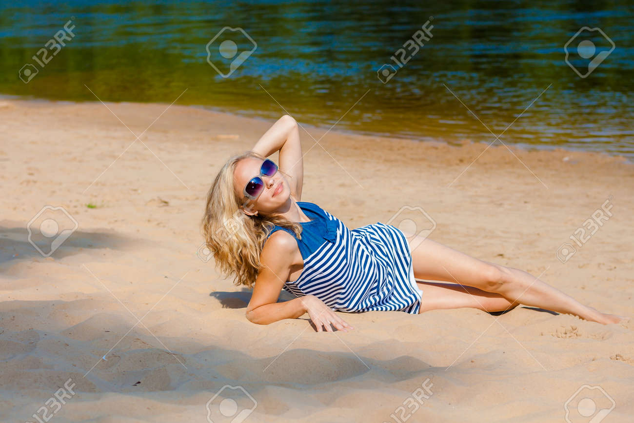 Garota De Biquíni Loira Sexy Posando Na Praia. Foto De Uma Mulher Jovem E  Bonita Com Cabelo De Sopro Relaxante Na Areia Em Uma Praia Fotos, retratos,  imágenes y fotografía de archivo