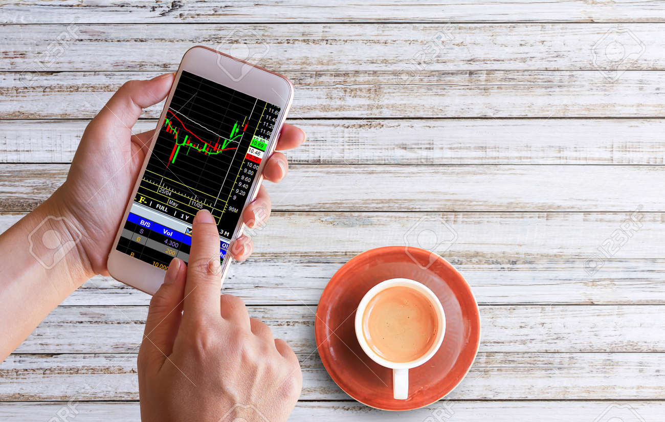Women Hand Holds The Phone For Trading Forex Or Stocks And See - 