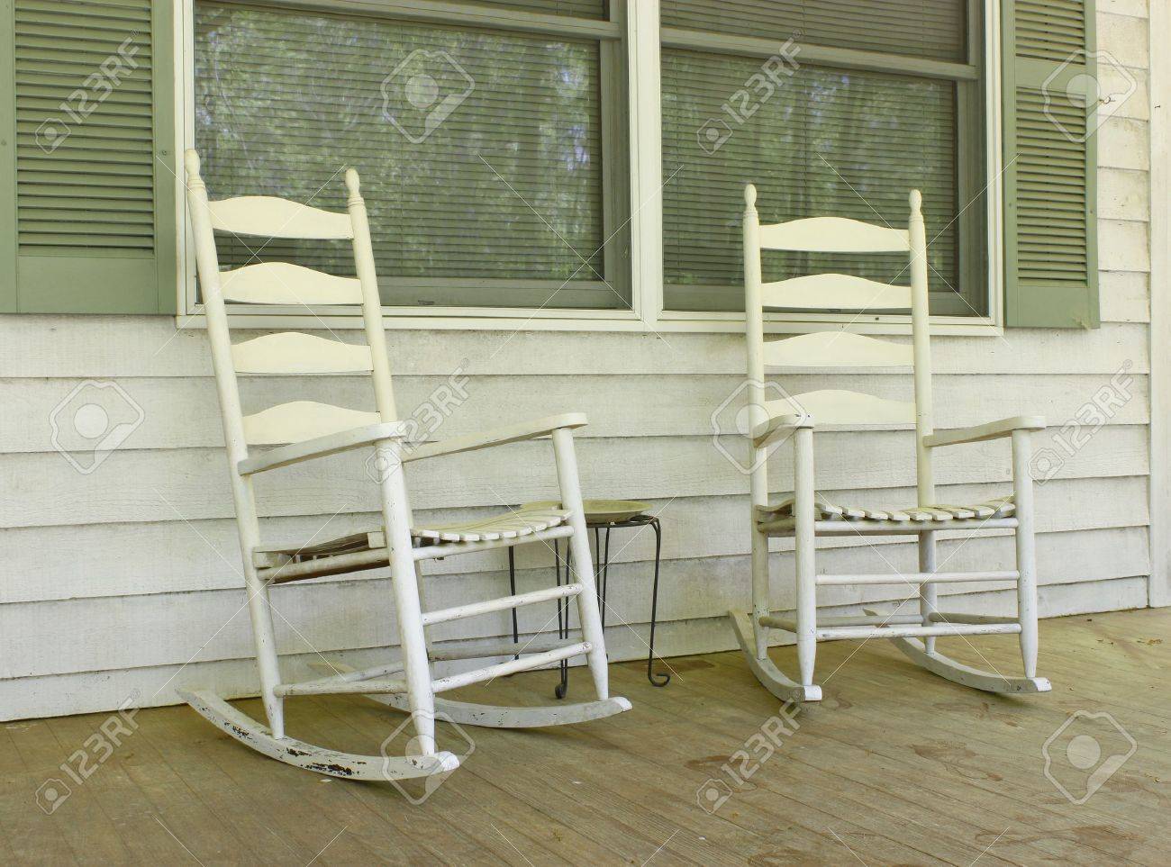 two old white painted wooden rocking chairs on a front porch stock