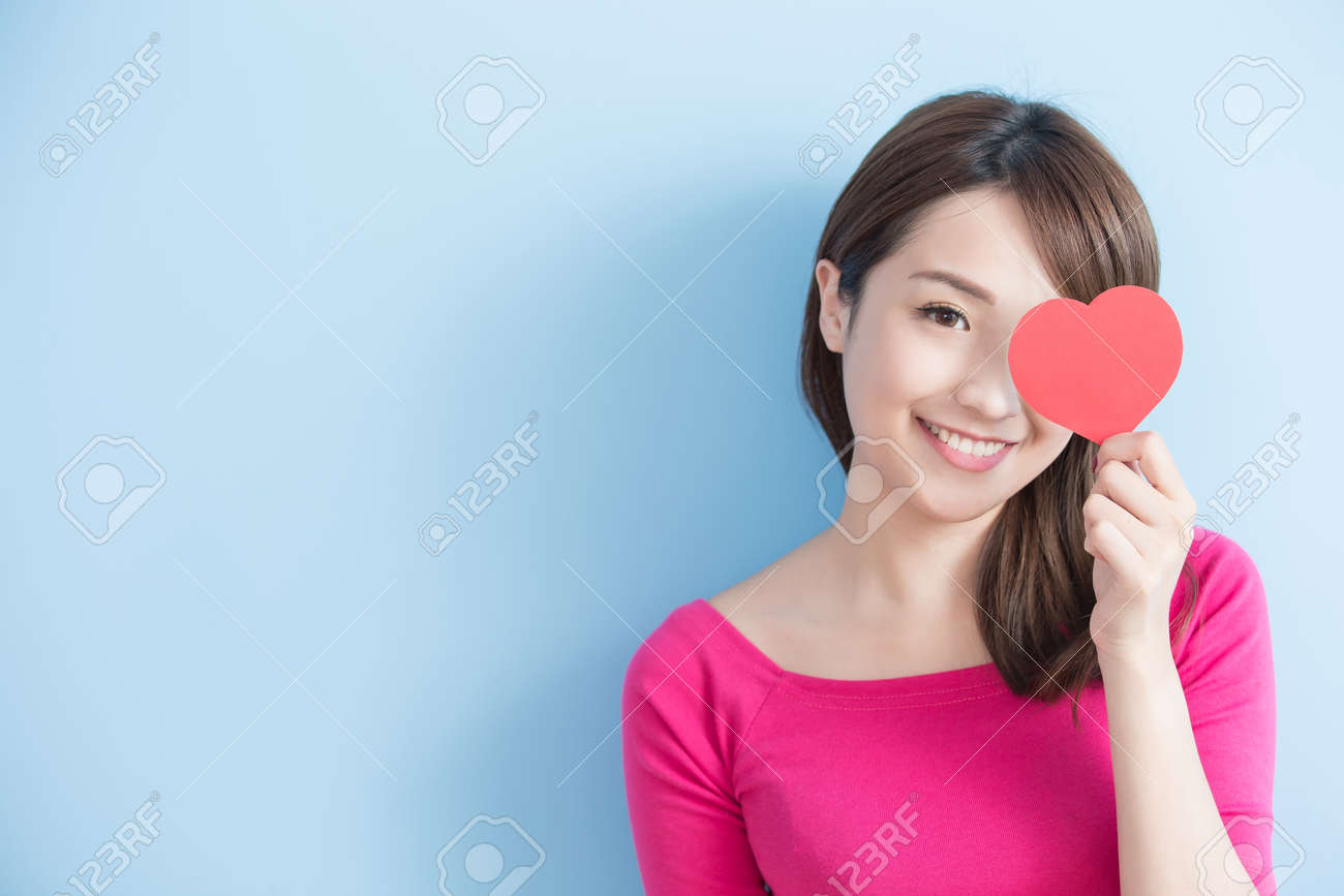 Attractive young woman holding red love hearts over eyes isolated on blue background - 71232980 Attractive young woman holding red love hearts over eyes isolated on blue background - 71232980