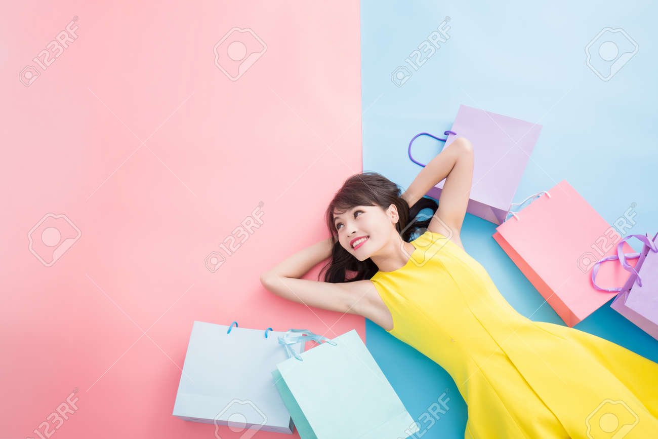 woman take shopping bag happily and look copy space on the blue and pink background - 108677580 woman take shopping bag happily and look copy space on the blue and pink background - 108677580