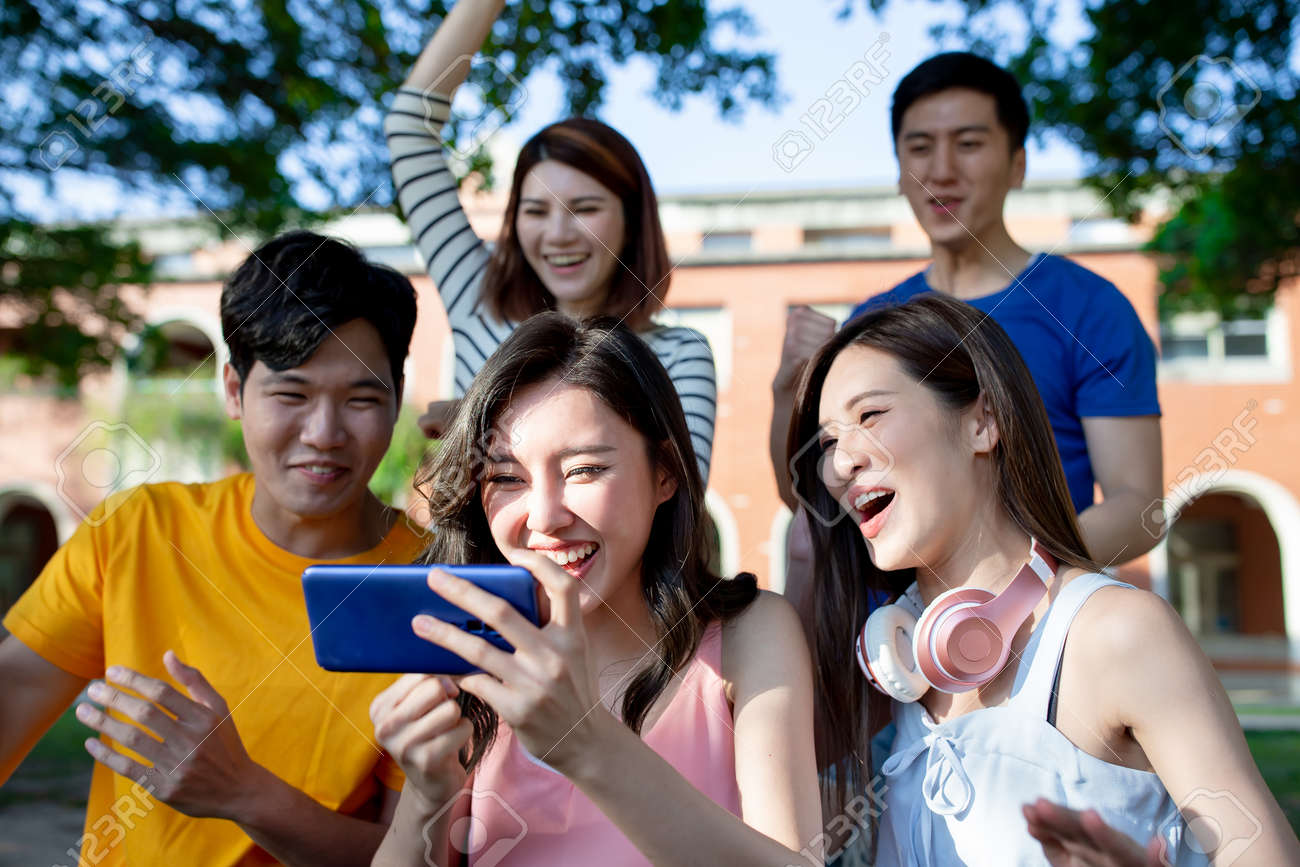 Group Of Young Asian People Sitting And Addicted To Playing Mobile