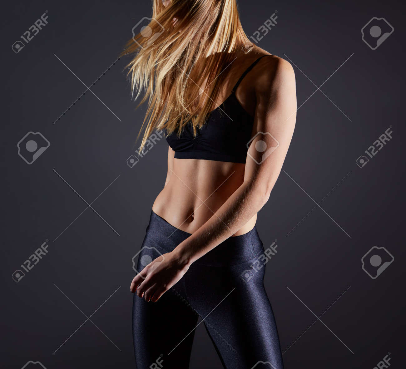 Sportive blonde girl on the background of the black wall of the gym. Body relief and hair sweep - 169021092 Sportive blonde girl on the background of the black wall of the gym. Body relief and hair sweep - 169021092