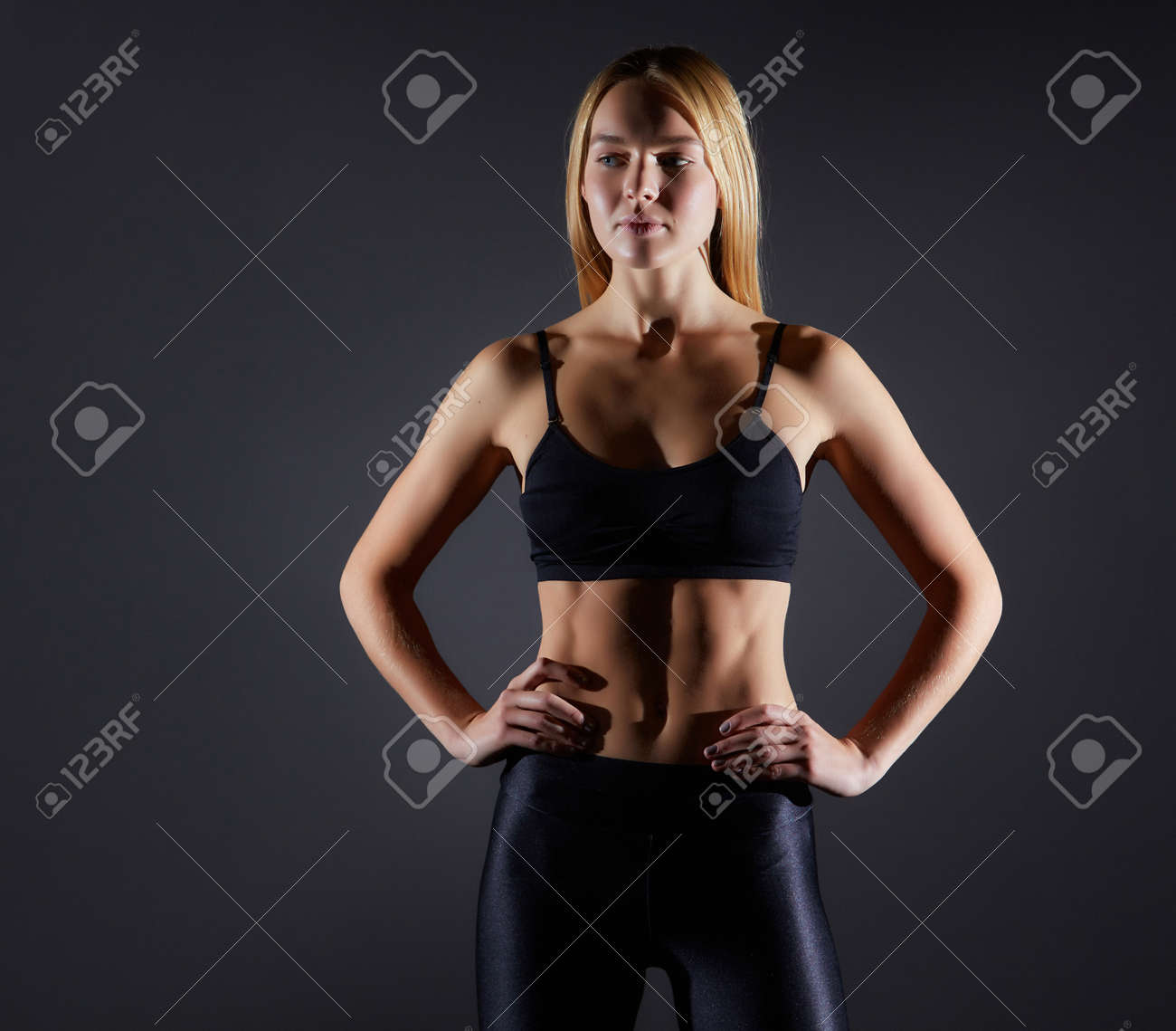 Sportive blonde girl on the background of the black wall of the gym. Body relief and hair sweep - 169021116 Sportive blonde girl on the background of the black wall of the gym. Body relief and hair sweep - 169021116