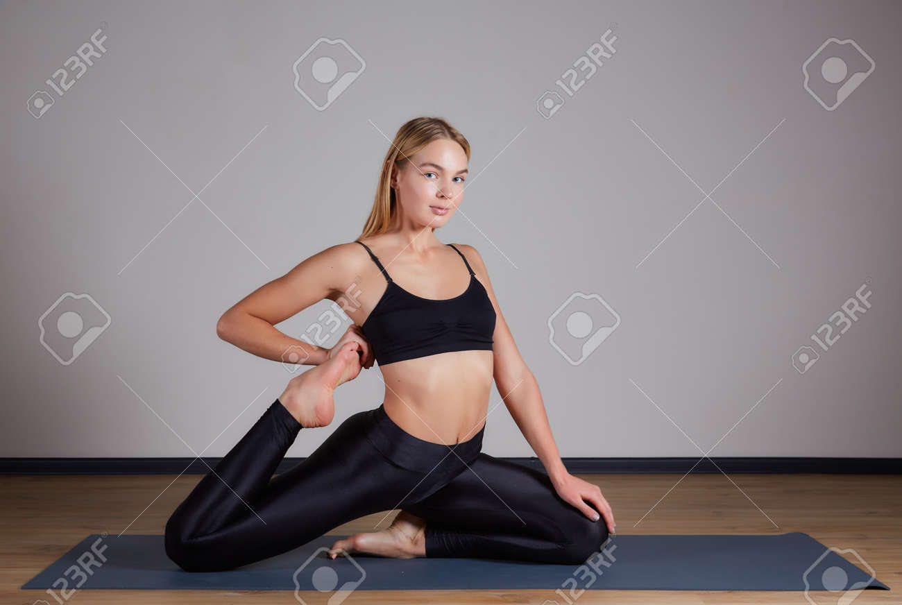 Young yogi woman practicing yoga concept, doing One Legged King Pigeon exercise, Eka Pada Rajakapotasana pose. Working out, wearing sportswear bra and pants, silhouette, loft studio background - 169021129 Young yogi woman practicing yoga concept, doing One Legged King Pigeon exercise, Eka Pada Rajakapotasana pose. Working out, wearing sportswear bra and pants, silhouette, loft studio background - 169021129