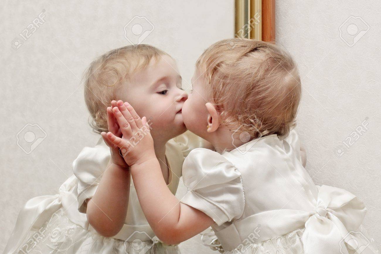 Cute Baby Kissing A Mirror With Oneself Reflection Stock Photo