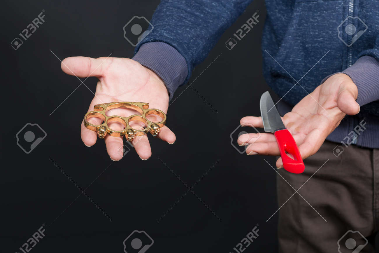 男の手のひらにブラスナックルとナイフ。アメリカ人の手に金属製のブラスナックル。戦いで禁じられた武器、犯罪者。白人男性が両手でブラスナックルを持って見せますの写真素材・画像素材  Image 172492895