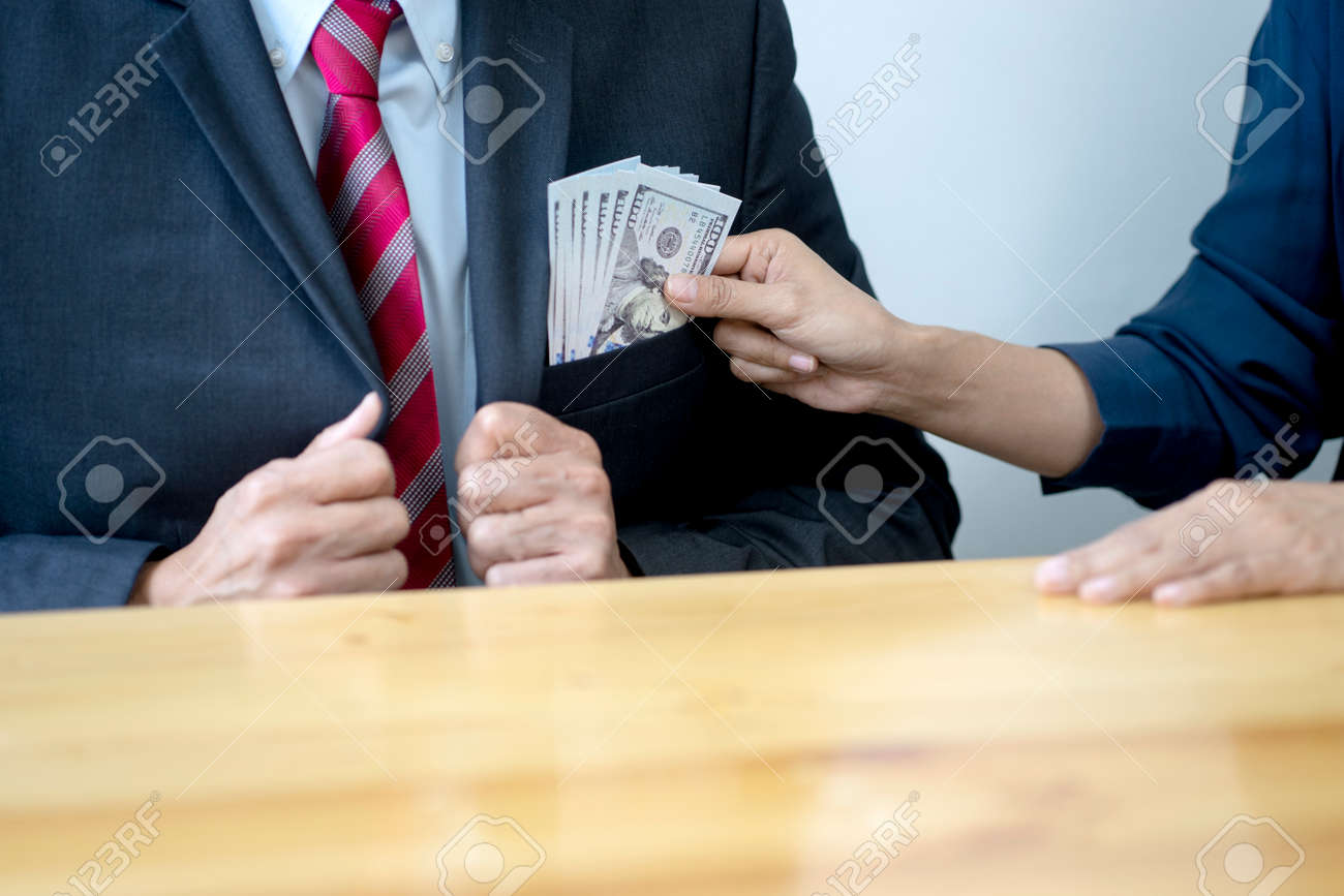Businessmen or customers are putting money into the pocket of the officer's shirt to help them run the business bribe or corruption concept - 169229774 Businessmen or customers are putting money into the pocket of the officer's shirt to help them run the business bribe or corruption concept - 169229774