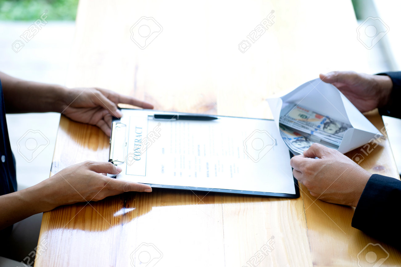 The businessman or staff is holding an envelope containing the money the businessman has submitted and offered to help them sign a contract bribe or corruption concept. - 169229781 The businessman or staff is holding an envelope containing the money the businessman has submitted and offered to help them sign a contract bribe or corruption concept. - 169229781