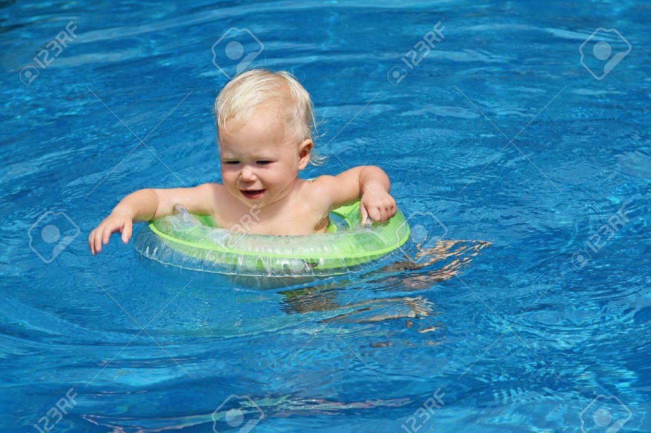 Baby swimming in the blue pool water - 10085749 Baby swimming in the blue pool water - 10085749