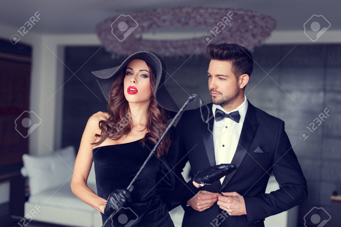Sexy dominatrix woman posing with whip and young macho lover in tux - 55303622 Sexy dominatrix woman posing with whip and young macho lover in tux - 55303622