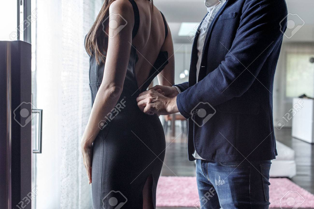 Macho man dressing woman into cocktail dress indoor, closeup - 61952739 Macho man dressing woman into cocktail dress indoor, closeup - 61952739
