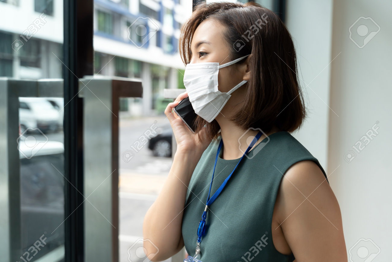 Portrait Asian business woman wearing hygienic mask talking on the phone outside office. - 162245012 Portrait Asian business woman wearing hygienic mask talking on the phone outside office. - 162245012