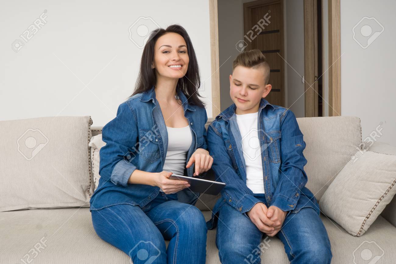 Happy Mother And Son Sitting On Sofa