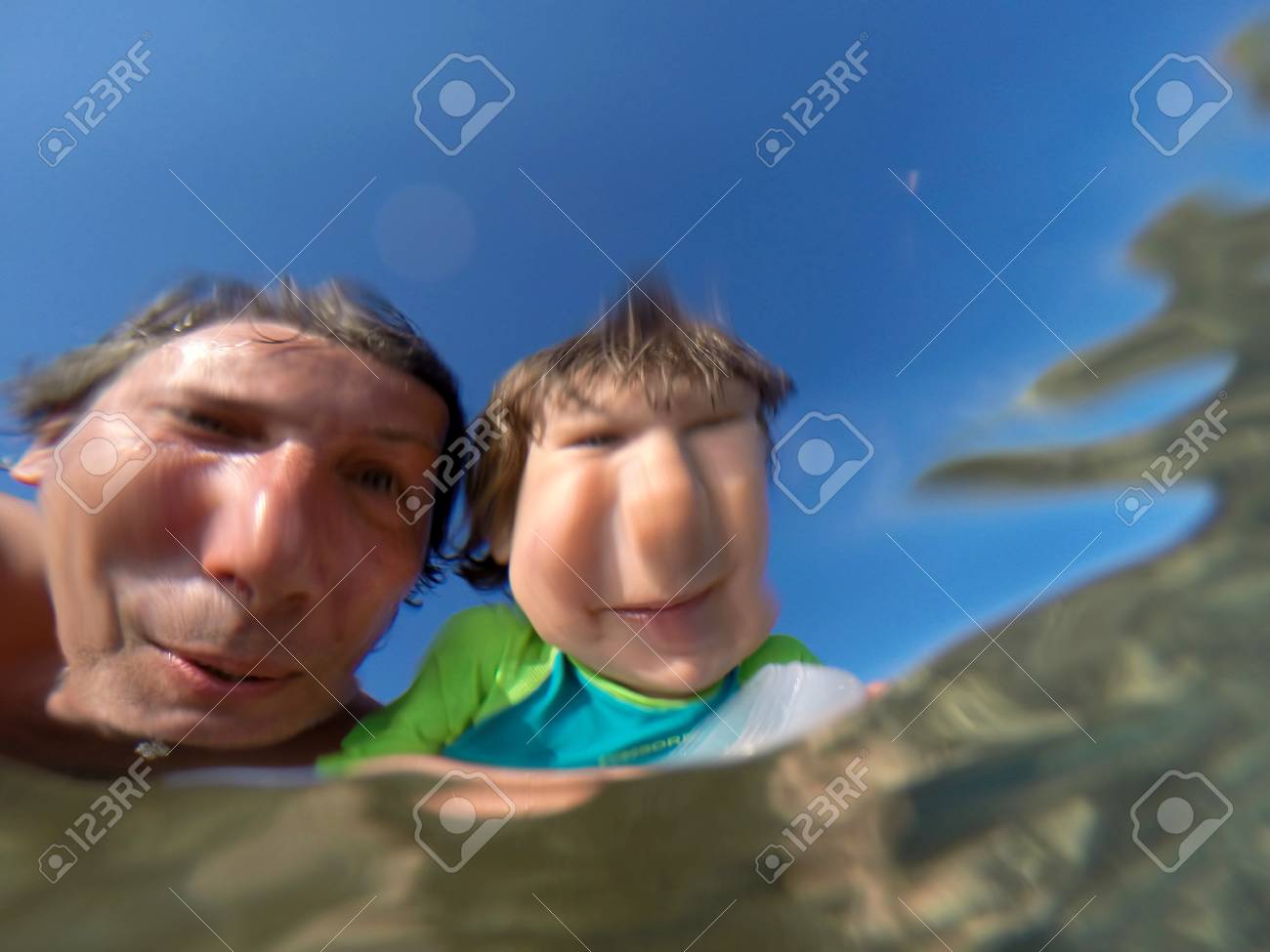 父と娘の幼児の海を楽しんでします 水 水中ビューを通して歪んだ顔を見る の写真素材 画像素材 Image