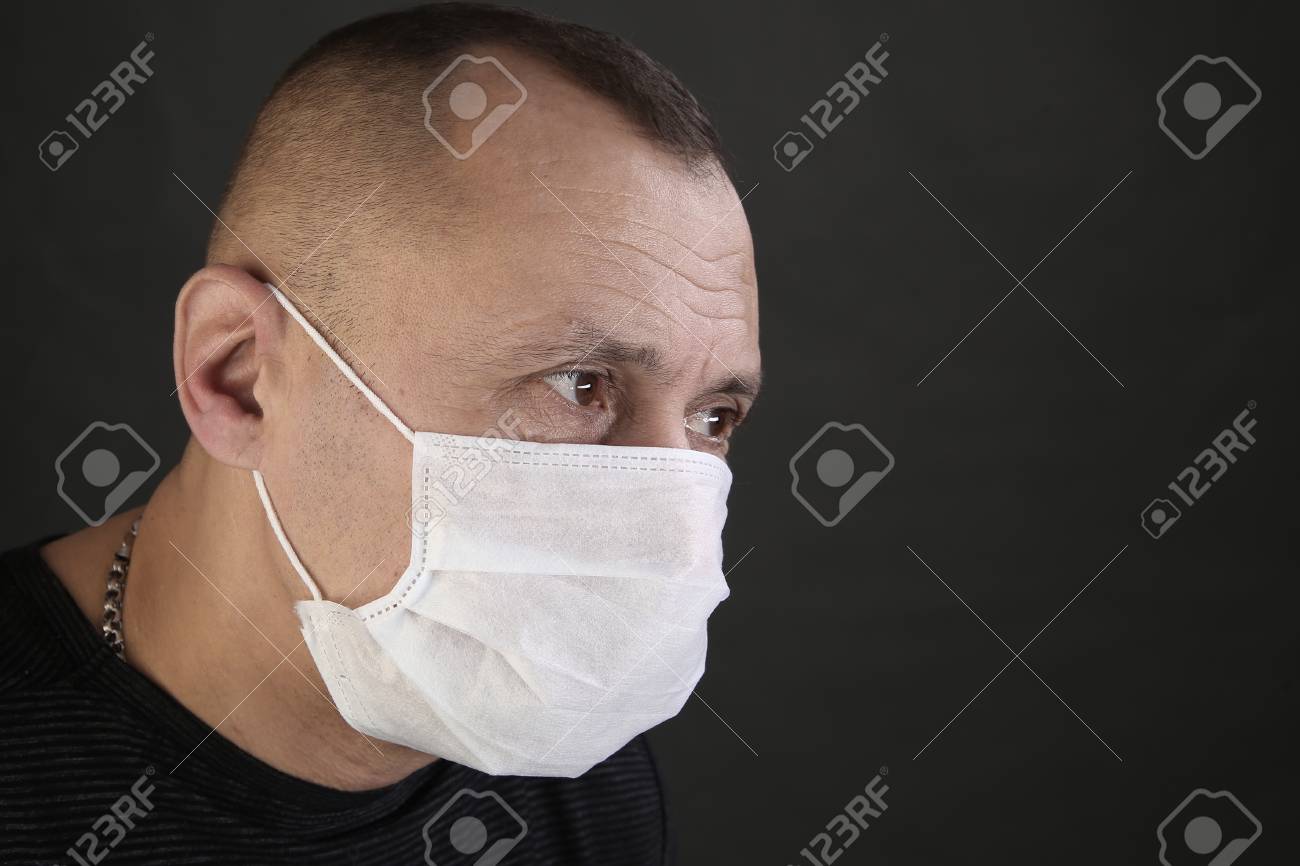 closeup portrait man in a black T-shirt and a medical mask on a gray background studio - 97213654 closeup portrait man in a black T-shirt and a medical mask on a gray background studio - 97213654