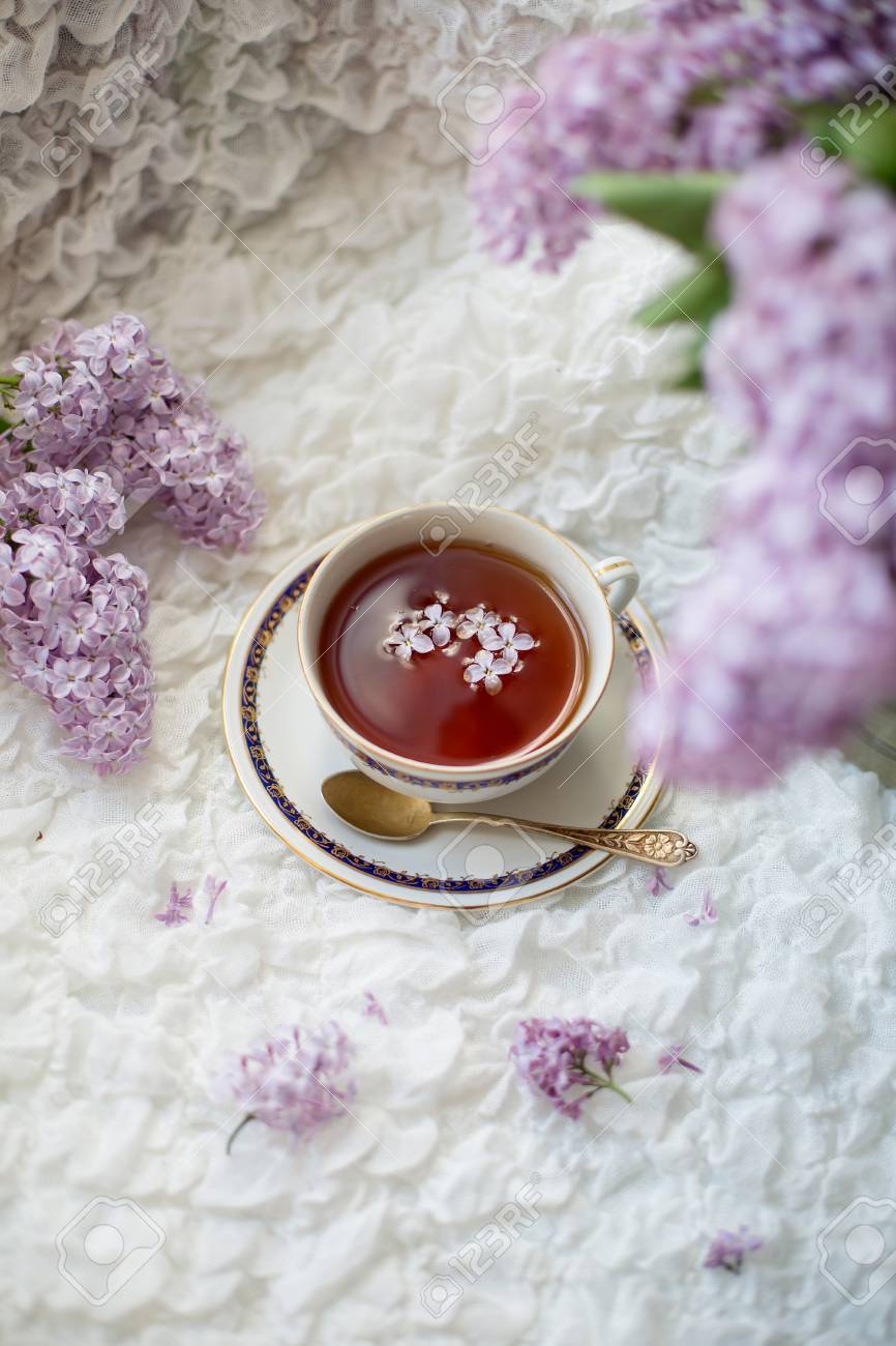 ライラックの花びらと白い繊細な繊維の背景にライラックの花の束の香り紅茶のカップ の写真素材 画像素材 Image