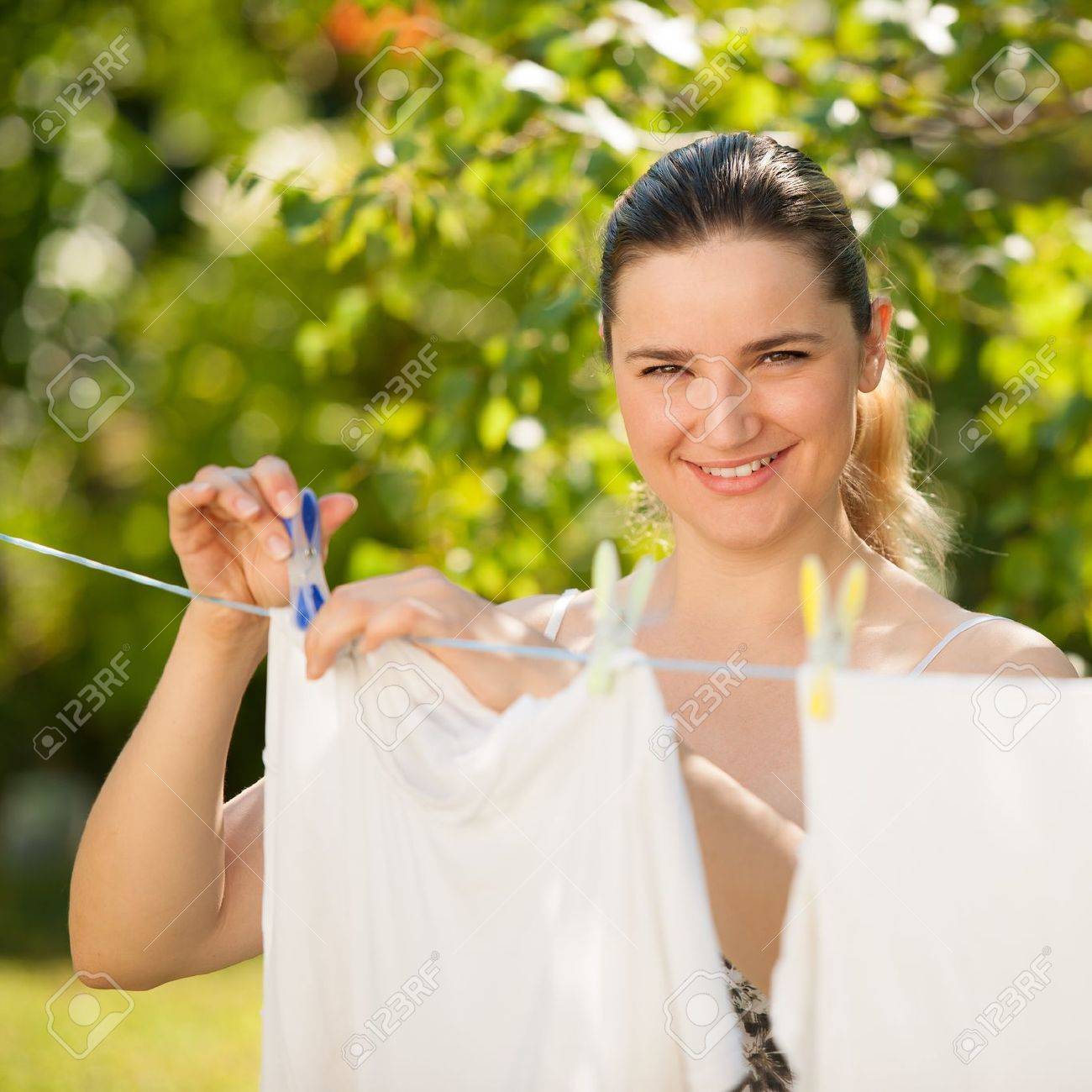 Young beautiful woman hanging laundry outdoor - 21962507 Young beautiful woman hanging laundry outdoor - 21962507
