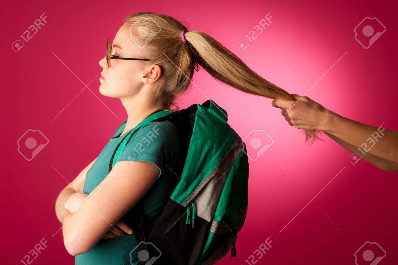 頑固な怒っている女学生が学校に行く抵抗します バックパックと大きな眼鏡 2 つ髪ツインテールの彼女を引いて誰か着ています の写真素材 画像素材 Image