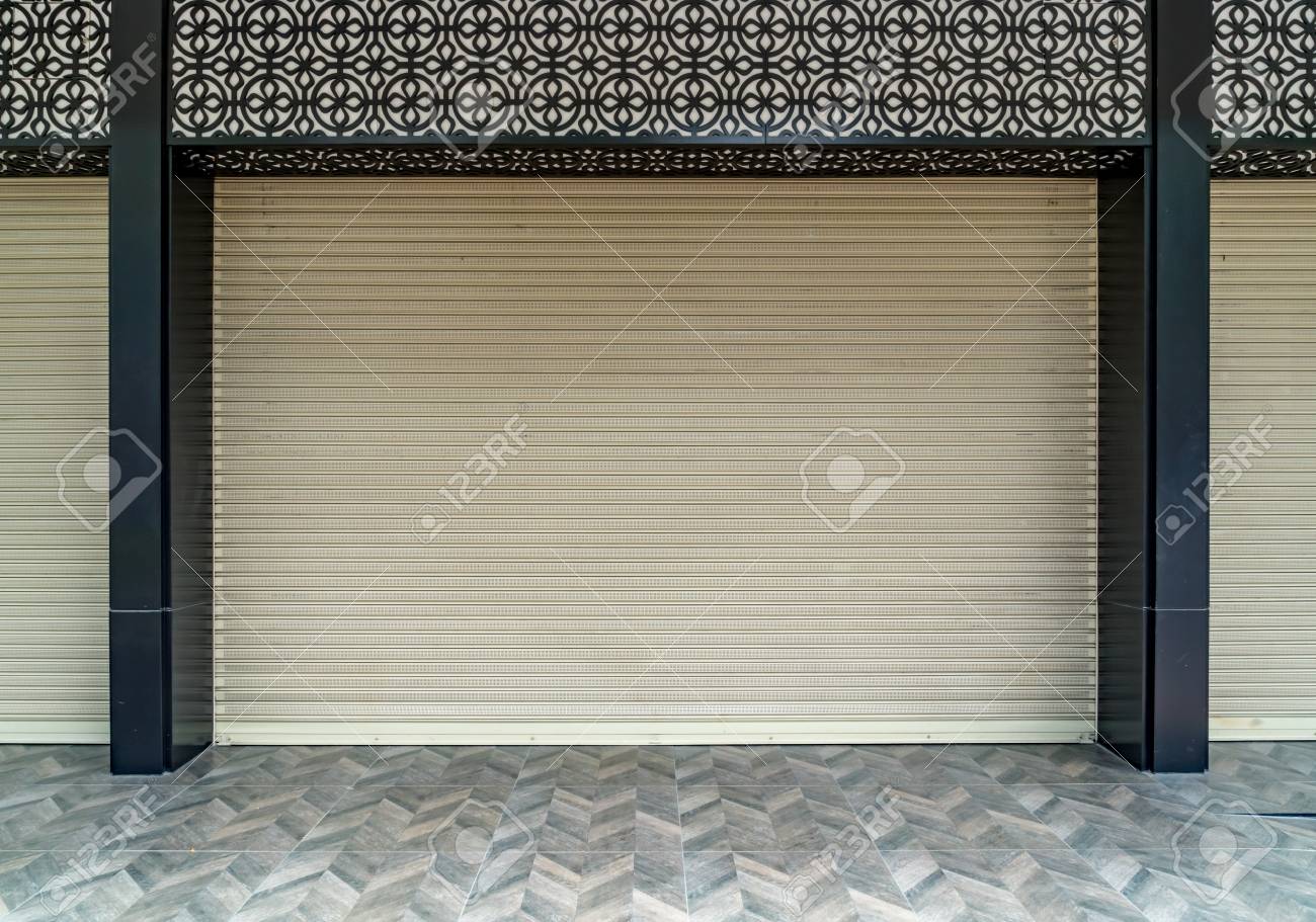 Old Beige Roller Shutter Door With Black Pole And Concrete Tiles Floor