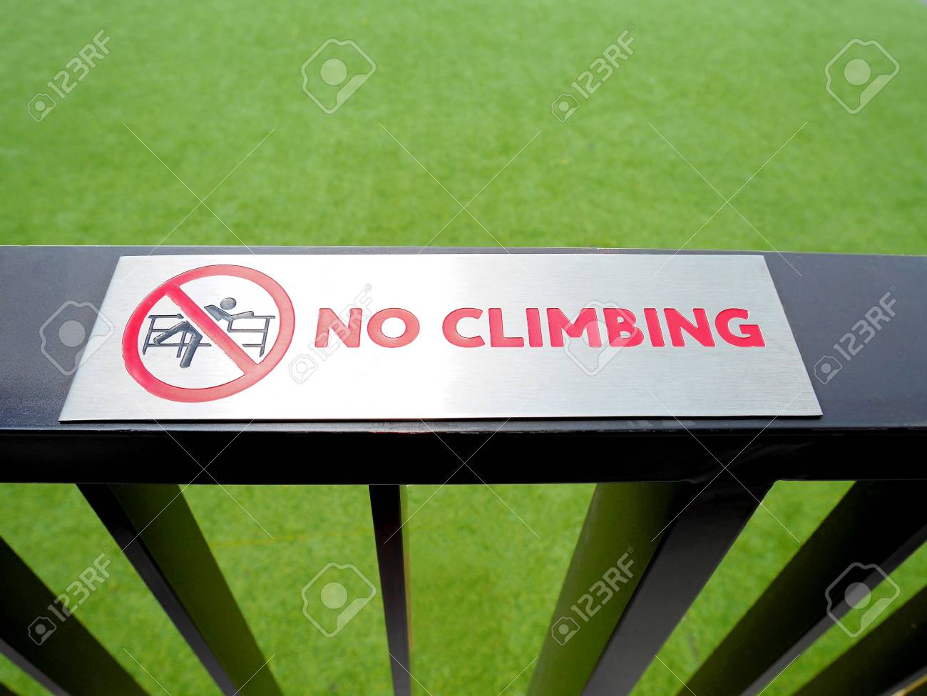 no climbing sign on the fence on green lawn background stock photo