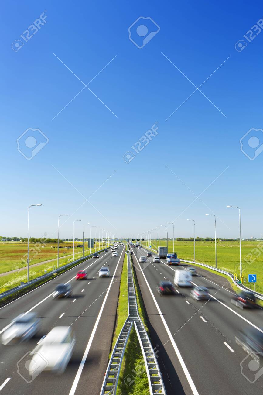 A highway with traffic through grassy fields on a bright and sunny day in The Netherlands. - 135125194 A highway with traffic through grassy fields on a bright and sunny day in The Netherlands. - 135125194