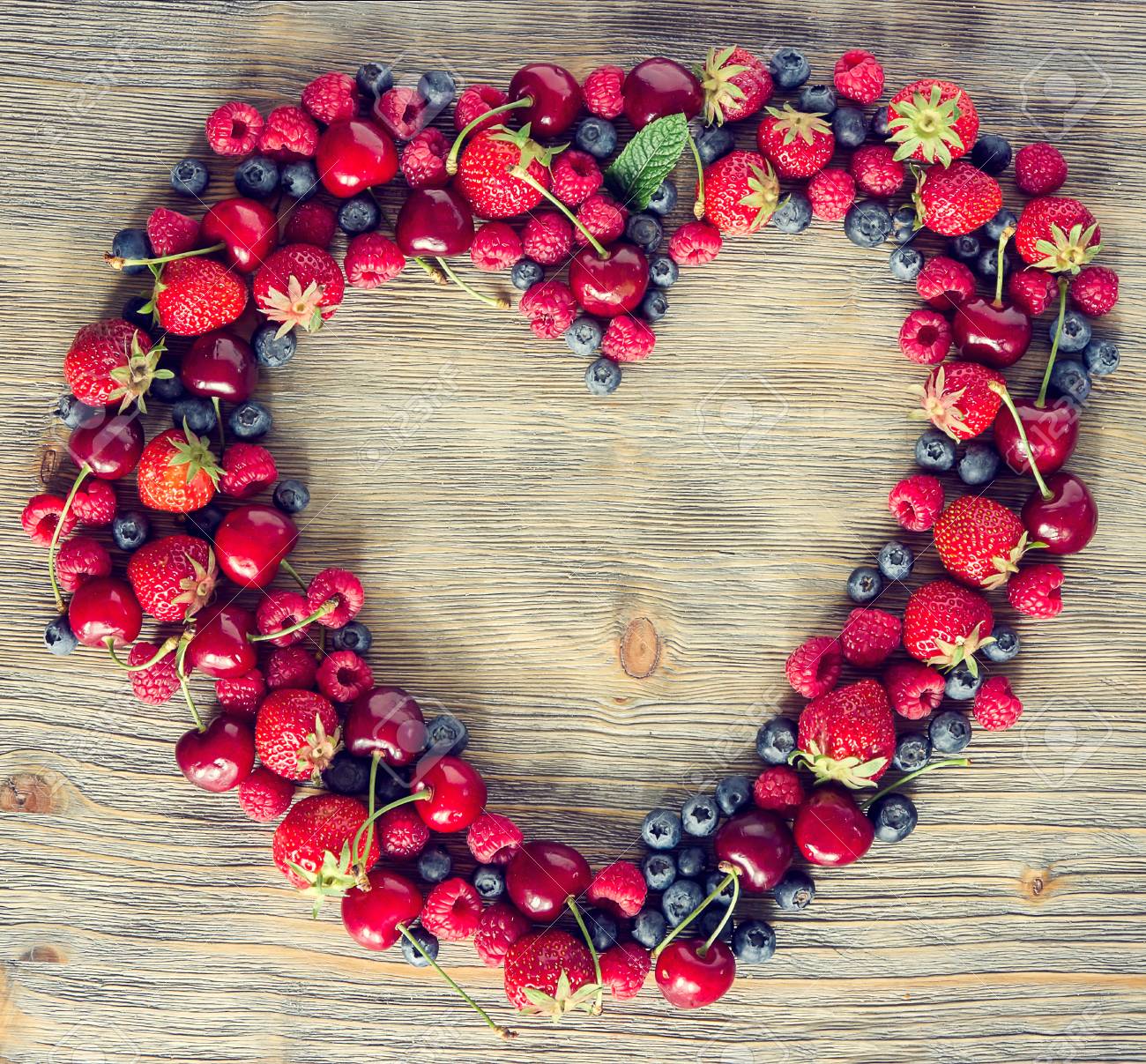 Fresh ripe berries, cherries, raspberries, blueberries lots of copy space, wooden background, summer fruits, harvest concept, vitamins food, heart shaped, square toned image - 41906000 Fresh ripe berries, cherries, raspberries, blueberries lots of copy space, wooden background, summer fruits, harvest concept, vitamins food, heart shaped, square toned image - 41906000