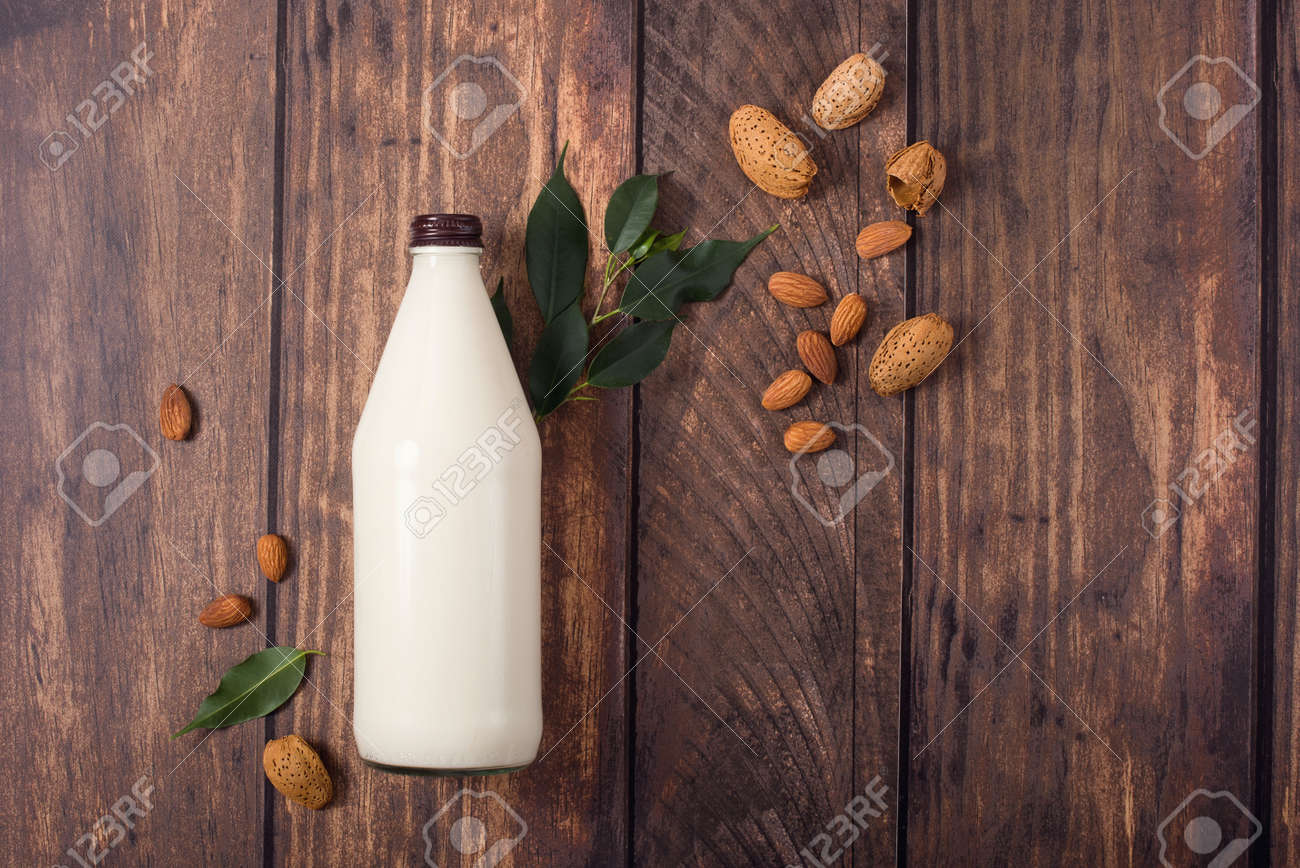 Plant based almond milk, healthy alternative drink in bottle on wooden background, ingredients for plant milk, vegan non dairy milk, flat lay, top view - 142635632 Plant based almond milk, healthy alternative drink in bottle on wooden background, ingredients for plant milk, vegan non dairy milk, flat lay, top view - 142635632