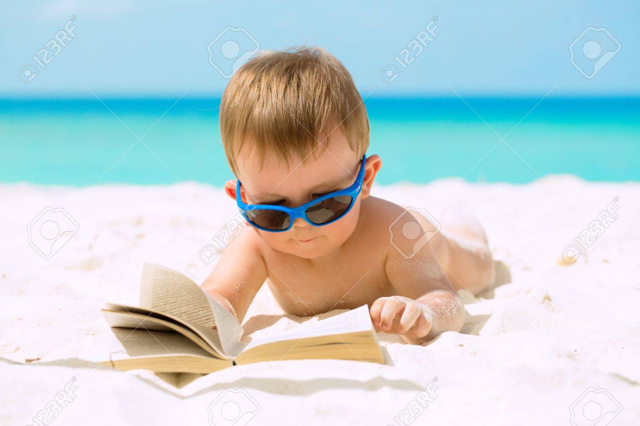 21865420-Cute-baby-boy-with-sunglasses-lying-on-white-sandy-beach-reading-the-book-and-having-his-first-tropi-Stock-Photo.jpg