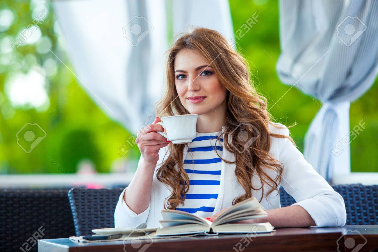 beautiful young girl in outdoor cafe reading a book and drinking coffee. phone. student. business woman - 40631496 beautiful young girl in outdoor cafe reading a book and drinking coffee. phone. student. business woman - 40631496