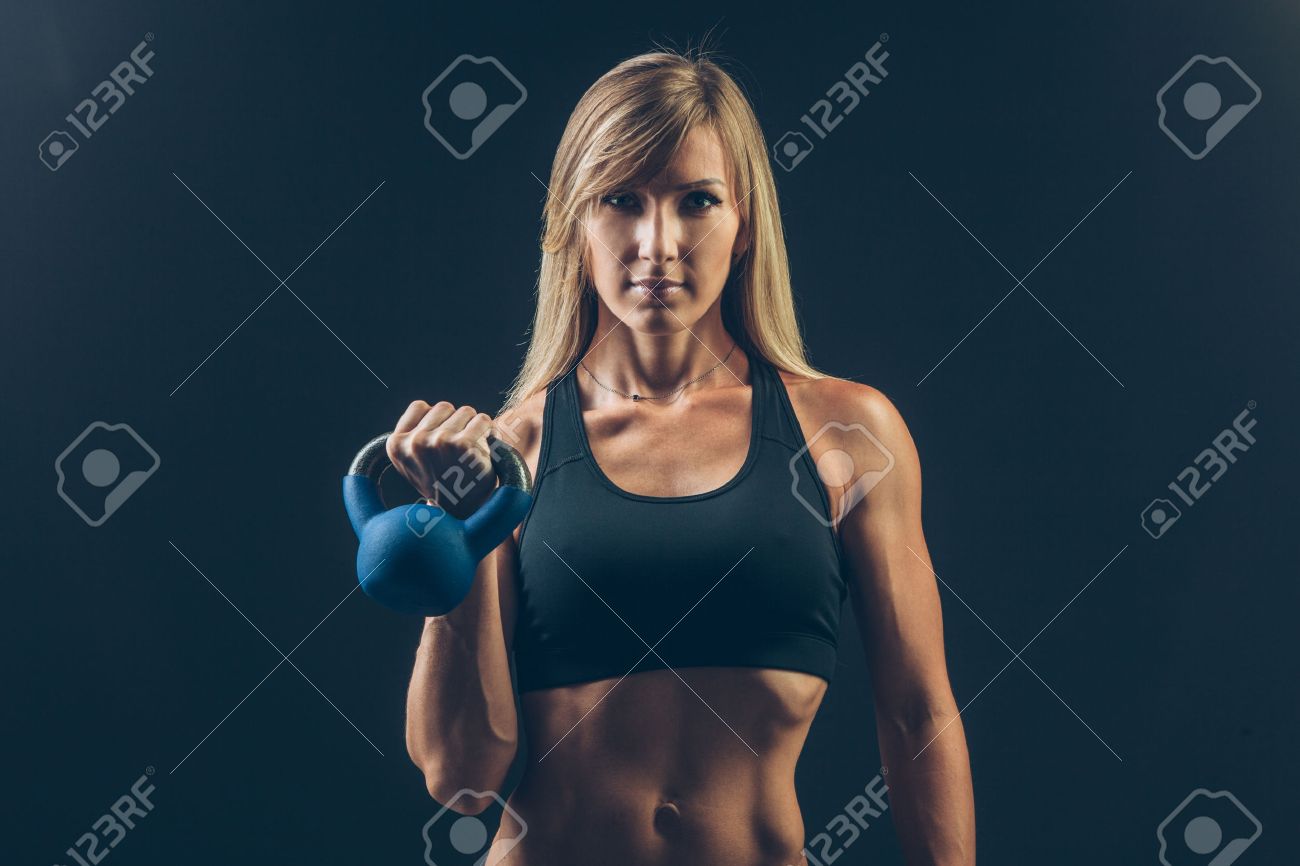 Fitness woman exercising crossfit holding kettlebell strength training biceps. Beautiful sweaty fitness instructor on blackoard background looking intense at camera. Asian Caucasian female model. - 43578001 Fitness woman exercising crossfit holding kettlebell strength training biceps. Beautiful sweaty fitness instructor on blackoard background looking intense at camera. Asian Caucasian female model. - 43578001