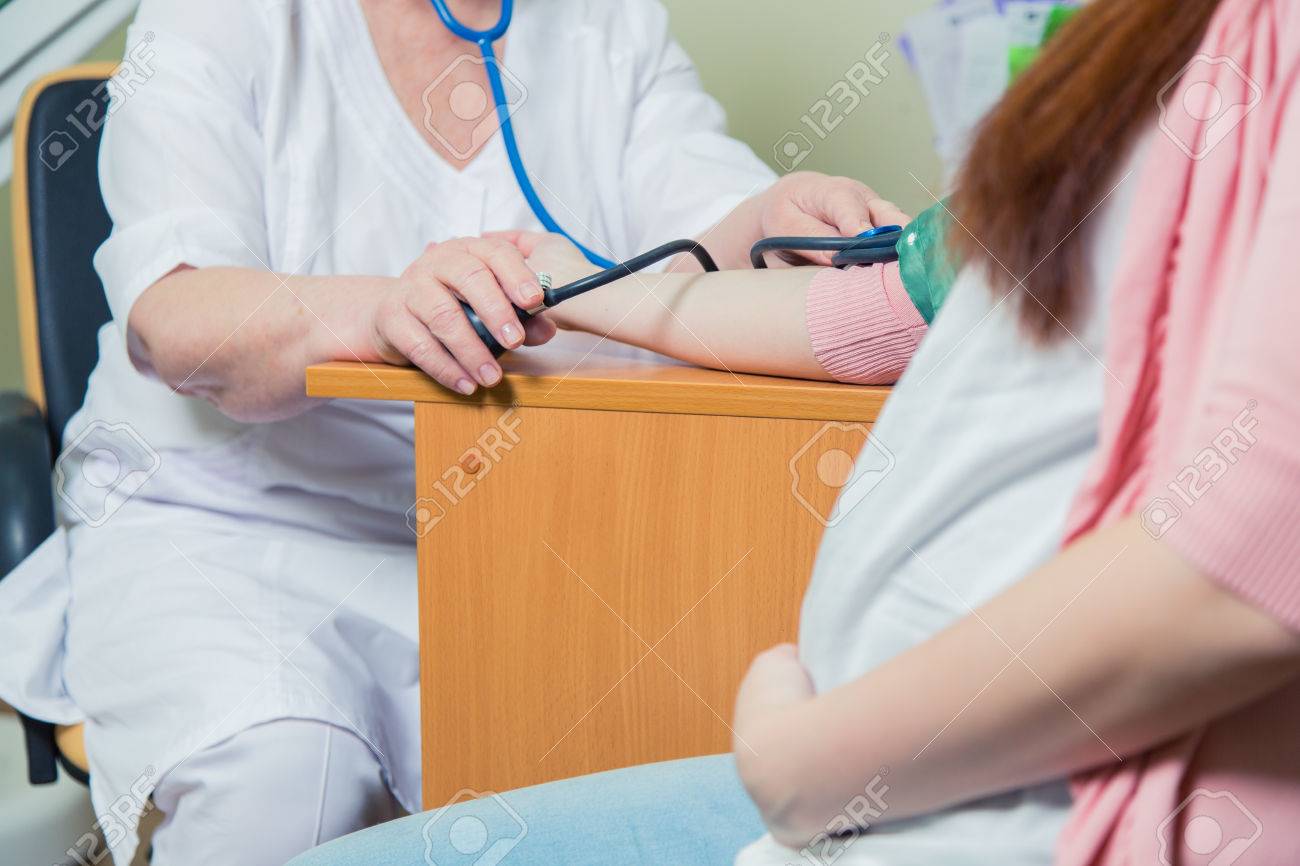 Doctor Measuring Blood Pressure Of Pregnant Woman In Clinic. - 56567531 Doctor Measuring Blood Pressure Of Pregnant Woman In Clinic. - 56567531
