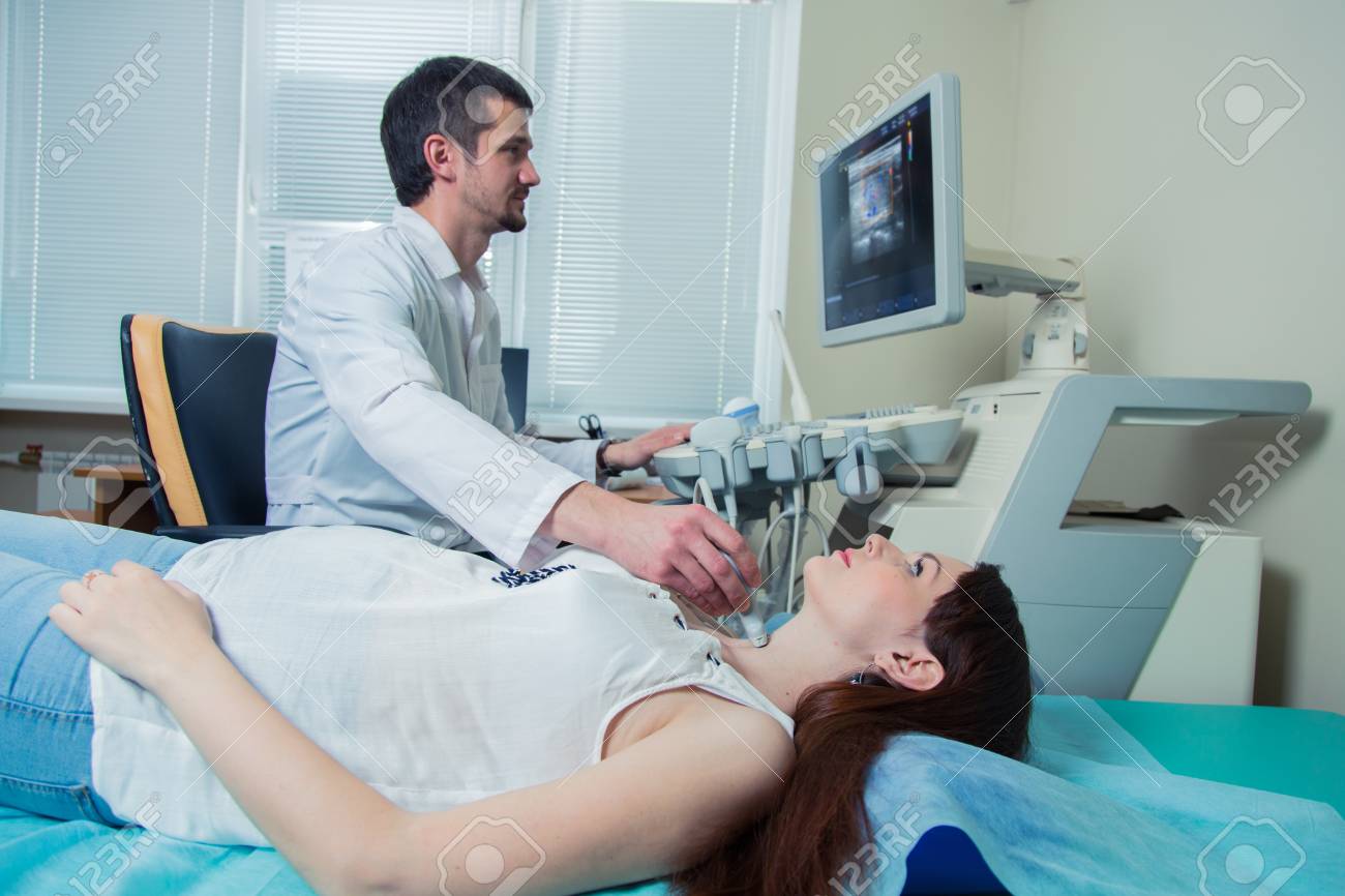 woman getting ultrasound of a thyroid from doctor. - 56567595 woman getting ultrasound of a thyroid from doctor. - 56567595