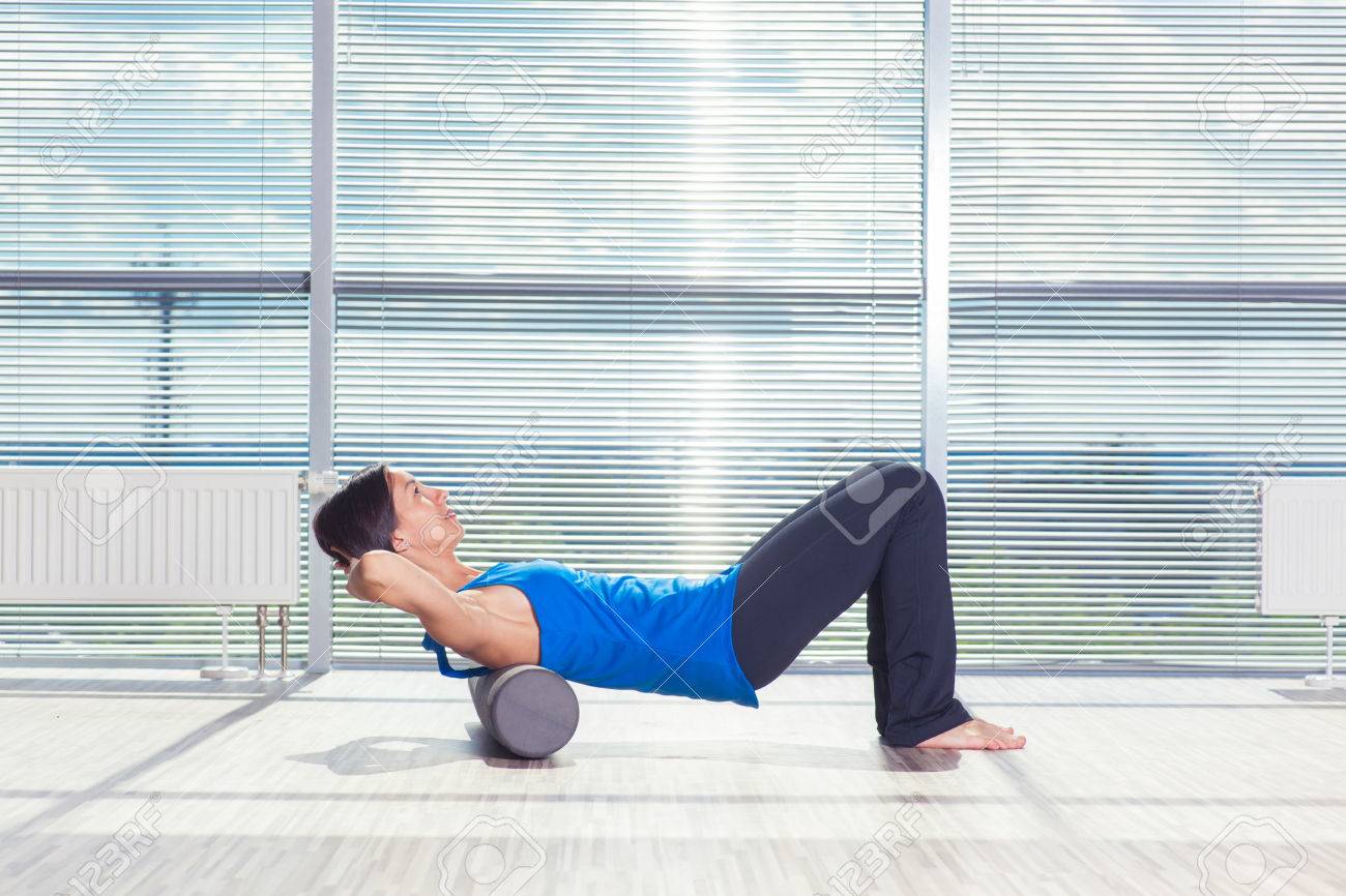 fitness, sport, training and lifestyle concept - woman doing pilates on the floor with foam roller. - 60759629 fitness, sport, training and lifestyle concept - woman doing pilates on the floor with foam roller. - 60759629