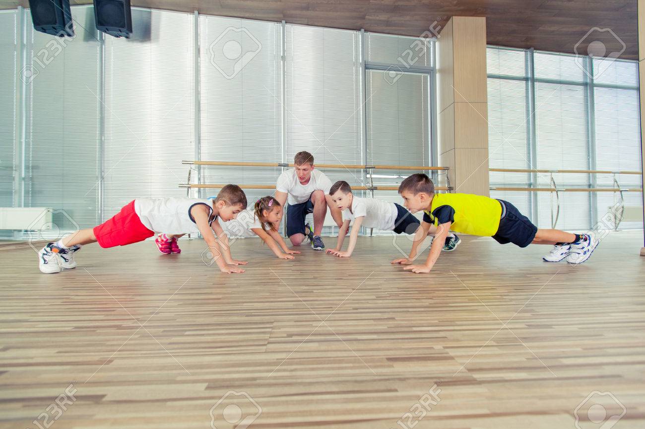 Group of children doing kids gymnastics in gym with nursery teacher. - 58396877 Group of children doing kids gymnastics in gym with nursery teacher. - 58396877